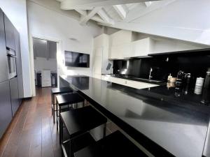 een grote keuken met een zwart aanrecht en stoelen bij Casa Cambria in Como +7 foto's