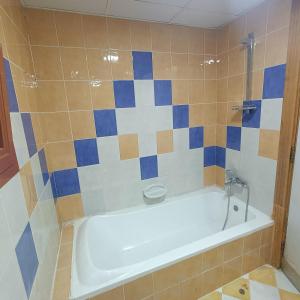 a bathroom with a white bath tub with blue and brown tiles at Al Basam Center in Dubai