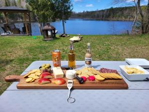 una mesa de picnic con comida y dos botellas de cerveza en BowLakeHouse - Lakefront Cottage with Beach en Bancroft