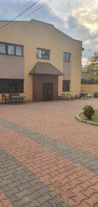 a building with benches in front of a brick courtyard at Noclegi pracownicze in Tomaszów Mazowiecki