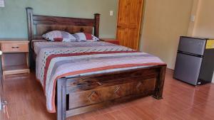 ein Schlafzimmer mit einem großen Holzbett und einem Kühlschrank in der Unterkunft Hotel Gitana Corcovado, y Tour operador in Drake