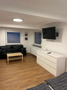 een woonkamer met een zwarte bank en een tv bij Home-for-you-Ferienwohnung Monteurwohnung in Buchen