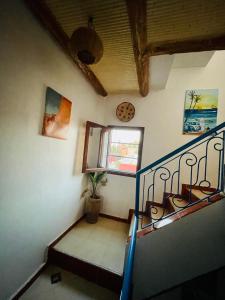 Una escalera en una casa con una ventana y una planta en Tamraght White Hostel en Tamraght Ouzdar