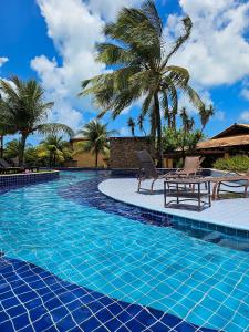 una piscina con 2 sillas y palmeras en Pipa Paradise, en Pipa