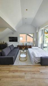 Neubau stilvolle Dachgeschoss City Wohnung في ميونخ: غرفة معيشة مع سرير وأريكة