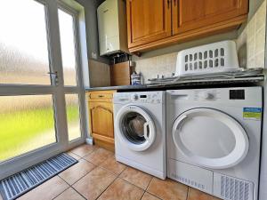 a laundry room with a washing machine and a window at Hill View House in Cheltenham