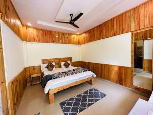 a bedroom with a bed in a room with wooden walls at The Stream Kasol in Kasol