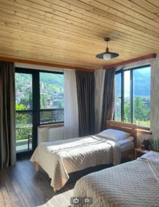 ein Hotelzimmer mit 2 Betten und großen Fenstern in der Unterkunft Lastili Inn Hotel in Mestia