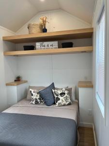 Łóżko w małym pokoju z półkami na ścianie w obiekcie The Abb Tiny Home w mieście Perry
