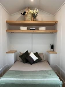 un letto in una piccola camera con scaffali in legno di The Big Bend Tiny Home a Perry