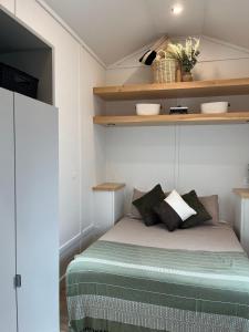 a small bedroom with a bed and shelves at The Big Bend Tiny Home in Perry