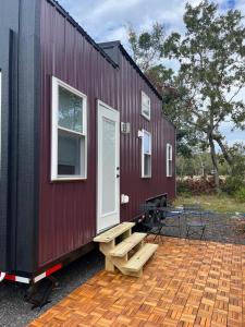 ein rotes winziges Haus mit einer Bank und einem Tisch in der Unterkunft The Mockingbird Tiny Home in Perry