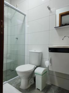 a white bathroom with a toilet and a shower at Maresias Suítes in Maresias