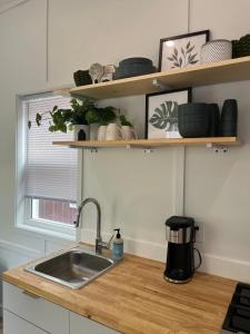 a kitchen counter with a sink and shelves at The Sam Tiny Home in Perry