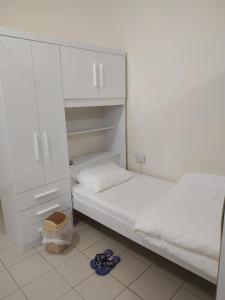 ドバイにあるRuby Star Hostel Dubai for Male- 4 R- 4の白いベッドルーム(ベッド1台、白いキャビネット付)