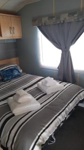 a bed with towels on it with a window at Holiday Caravan in Clacton-on-Sea