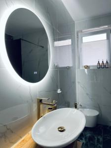 bagno con lavandino bianco e specchio di NewEra Apartment 1 
