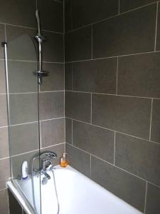 a bathroom with a bath tub with a shower and a sink at Spacious 2 Bed Elstree Borehamwood Hertfordshire in Elstree