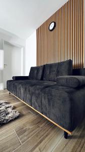 un divano nero in una stanza con un orologio sul muro di NewEra Apartment 1 