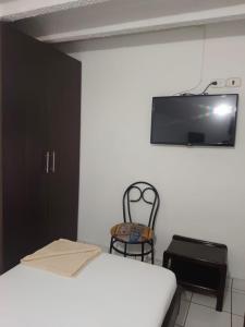 a bedroom with a bed and a chair and a flat screen tv at HOGAR DE PASO GUARACAO in Bucaramanga