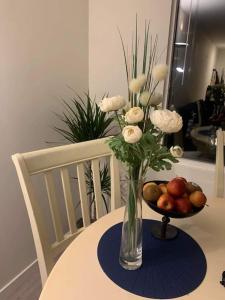 a vase with flowers and a bowl of fruit on a table at SylviaBo in Skien