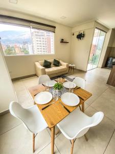 a living room with a wooden table and white chairs at Hermoso Departamento completo en la mejor zona de Cochabamba in Cochabamba