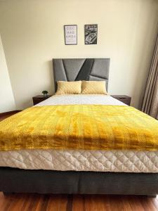 a bedroom with a large bed with a yellow blanket at Hermoso Departamento completo en la mejor zona de Cochabamba in Cochabamba