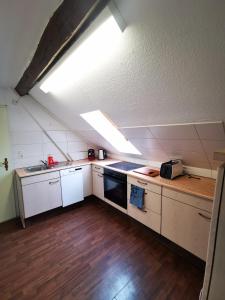 una cocina en el ático con armarios blancos y tragaluz en Schwert Apartment Verden, en Verden