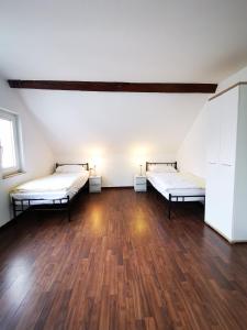 Habitación vacía con 2 camas y suelo de madera. en Schwert Apartment Verden, en Verden
