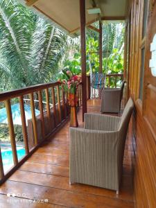 a porch with two chairs and a vase of flowers at CHOMI HOUSE TAMBOPATA in Puerto Maldonado