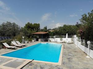 a swimming pool with chairs and a gazebo at Villa Evridiki - Walking distance to beach in Porto Heli