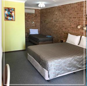 a bedroom with a bed and a brick wall at Alyn Motel in Gunnedah