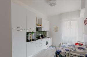 una cucina con armadi bianchi, un tavolo e una sala da pranzo di Casa di Kiki a Finale Ligure
