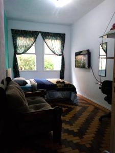 a bedroom with a bed and a window and a couch at Sobrado Tranquilo Centro in Porto Alegre