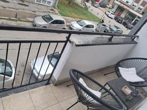 ein Balkon mit zwei Stühlen, einem Tisch und Autos in der Unterkunft Apartman 2E in Tuzla