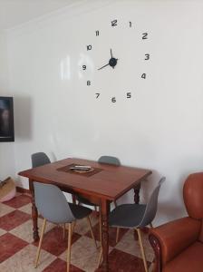 a dining room table with chairs and a clock on the wall at CASA SENDERO DEL RIO in El Bosque