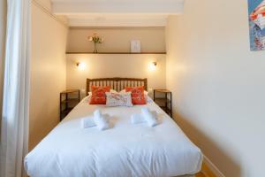 Schlafzimmer mit einem weißen Bett und roten Kissen in der Unterkunft TY MELEN - Charmante maison bretonne proche mer in Plouguerneau