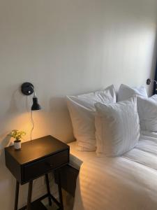 Cama con almohadas blancas y mesa con lámpara en Harbour Inn Hundested en Hundested