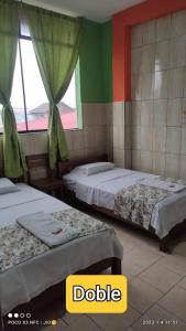 1 dormitorio con 2 camas y ventana en HOSTAL AKEMI, en Yurimaguas