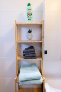 a wooden shelf with towels and a bottle of soap at Tram station rooms by CityPillow since 2019 in Hesperange