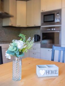 a vase with flowers on a table with a home sign at Tram station rooms by CityPillow since 2019 in Hesperange