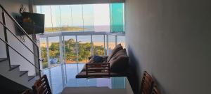 a dog sitting on a couch in a room with a large window at Cobertura Duplex Vista Mar Meaipe in Guarapari