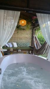 uma banheira de hidromassagem num quarto com duas redes de descanso em Cabana Encantos da Lagoa em Imbituba