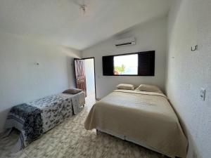1 dormitorio con 2 camas y ventana en Casa em FRENTE À PRAIA, ao lado do Nord Hotel - Tabatinga en Conde