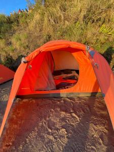 an orange tent is set up on a hill at Gunung Batur camp in Kintamani