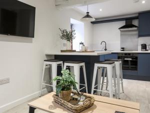 a kitchen with blue cabinets and a table and stools at Llety Pen Deitsh 2 in Caernarfon