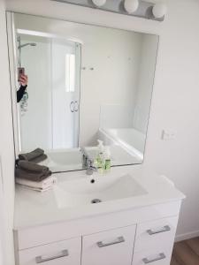 uma pessoa a tirar uma foto de um lavatório de casa de banho com um espelho em Paihia Retreat em Paihia