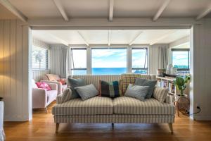 a living room with a couch and some windows at Clifftop Sanctuary in Oneroa