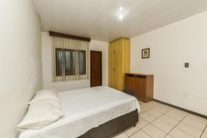 a bedroom with a white bed and a window at Rental Florianópolis - Acomodações Residenciais in Florianópolis