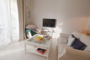 a white living room with a couch and a tv at Casa Lura at Gjiri i Lalzit, San Pietro Beach in Durrës